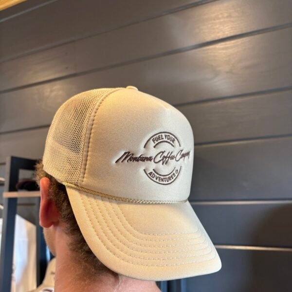 Montana Trucker Hat A man wearing a tan trucker cap with Fuel Your Adventures and Montana Coffee Company written on the cap.